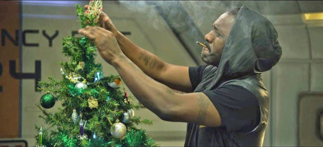 Film still of a man decorating a small Christmas tree
