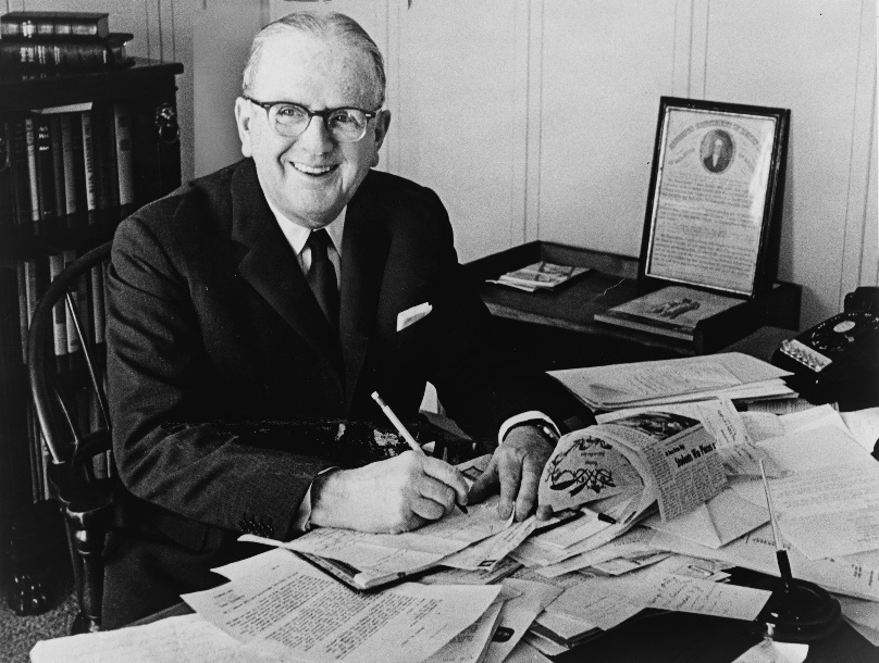 Norman Vincent Peale smiling at his desk.